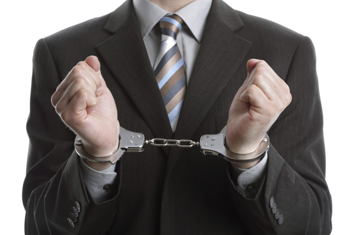 Corporate crime concept, businessman wearing handcuffs