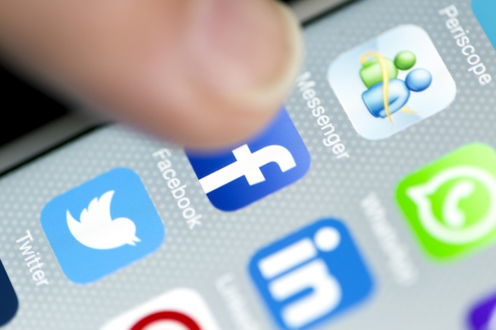 Istanbul, Turkey - September 18, 2015: Apple Iphone 6 screen with social media applications of Whatsapp, Facebook, Twitter, Linkedin and Periscope while a male finger is about to touch on Facebook app.
