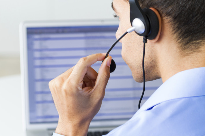 man wearing headset looking at computer monitor