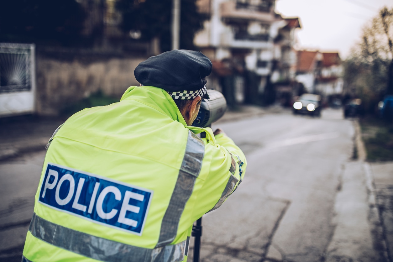 One man, traffic warden standing on the street, speed test with police radar.