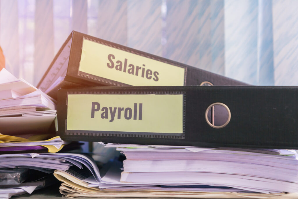 Payroll and salaries folders stack with label on black binder on paperwork documents summary report, HR human resources business and bookkeeping accountancy concept in busy offices
