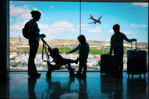 mother with kids and luggage looking at planes in airport mother with kids and luggage looking at planes in airport